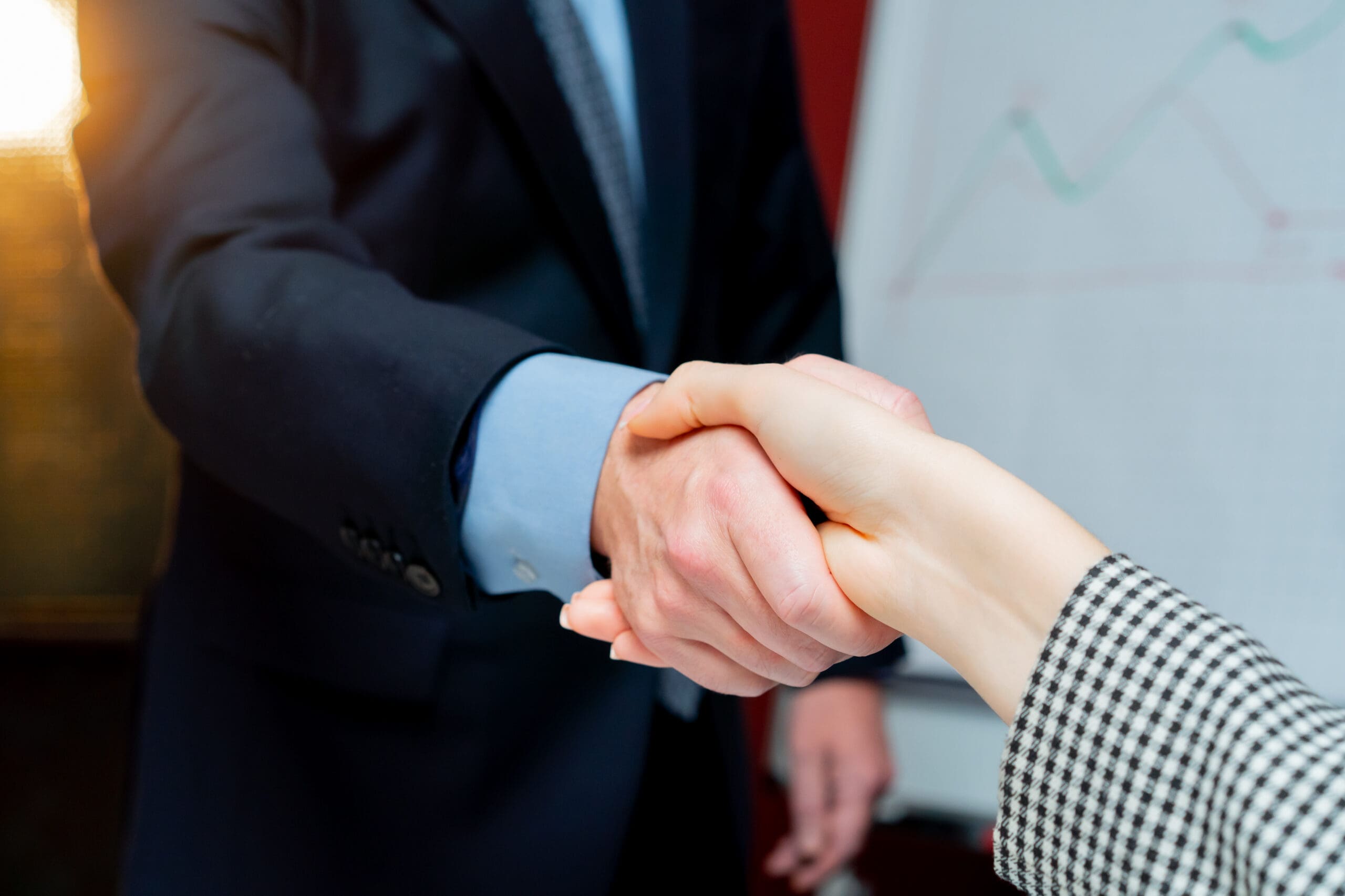 close-up in the office against the background of red walls a handshake between the boss and the employee