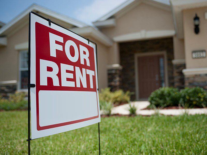 House with a red For Rent sign in front yard, representing rental property availability.