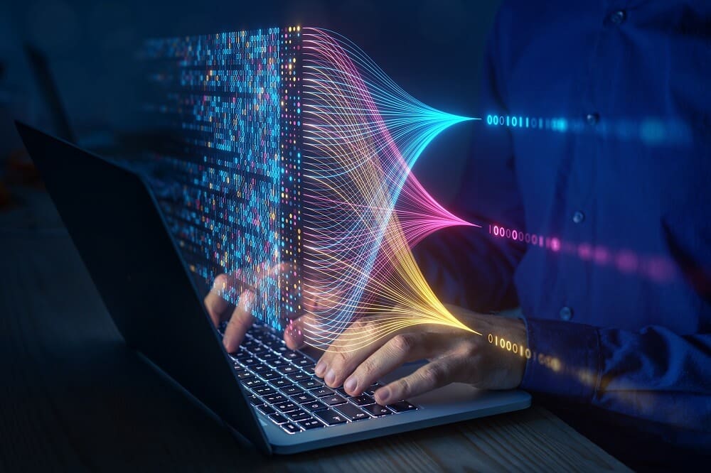 Person using laptop with colorful data flow visualization representing big data.