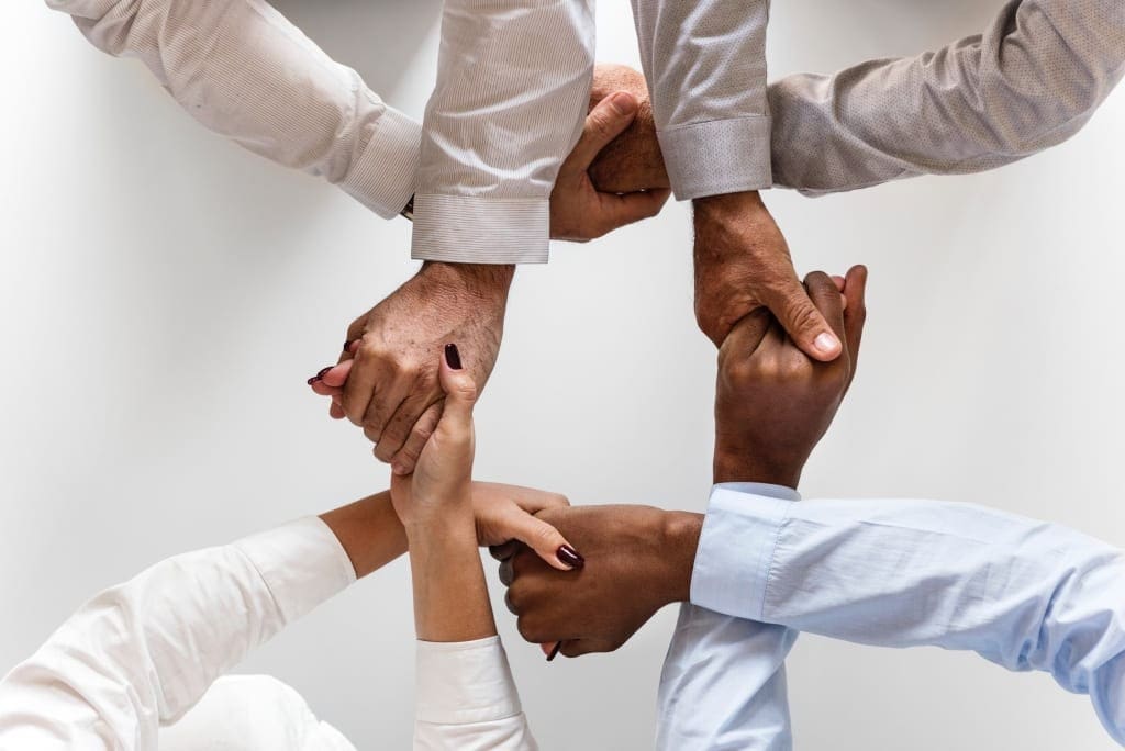 Group of diverse hands joined together symbolizing teamwork and unity.