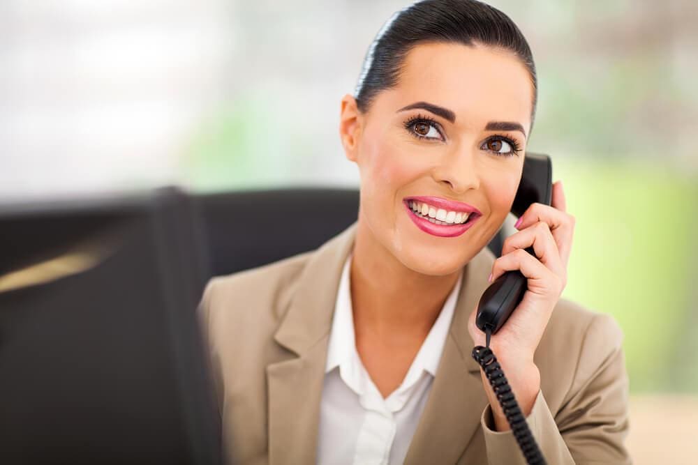 Smiling businesswoman talking on office phone during workday.